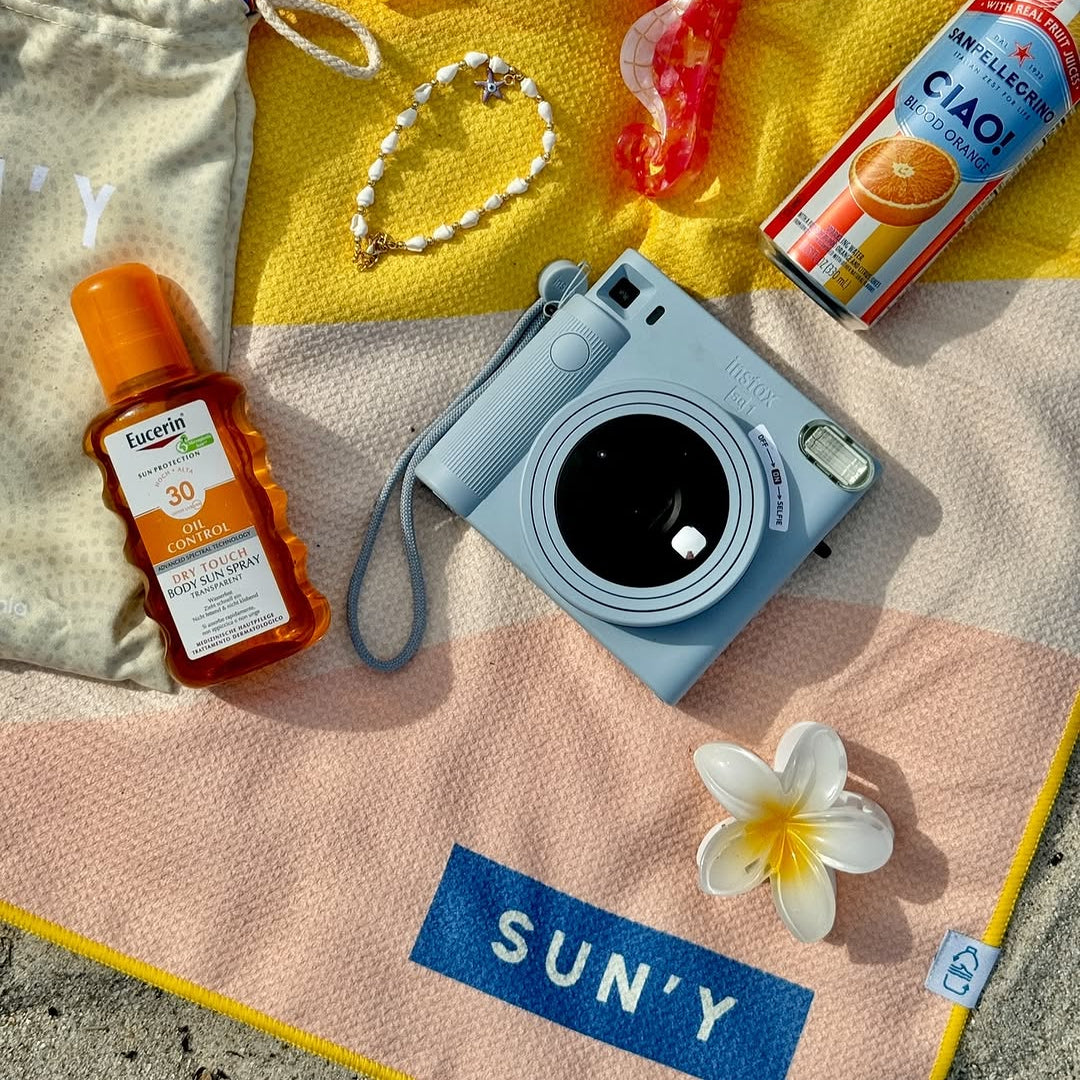 Camera, sunscreen, and other items on a SUN'Y beach towel (Boho).